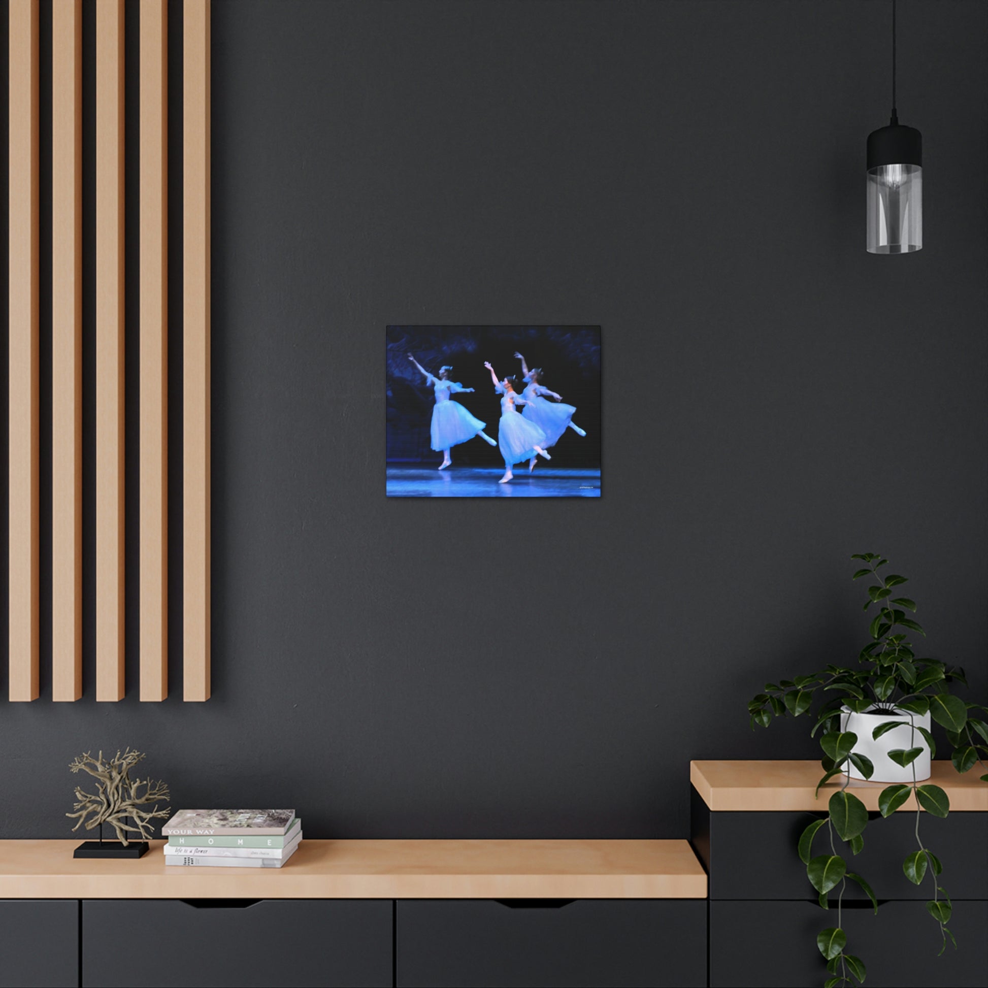 a photo of a painting in a home setting of three ballerinas performing on a stage dressed in white with light casting hues of blue