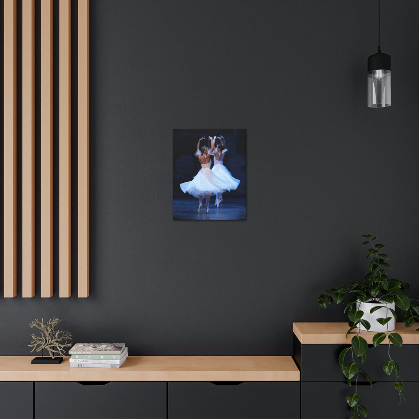 painting hanging on a dark wall of two ballerinas wearing tiaras and white dresses on point