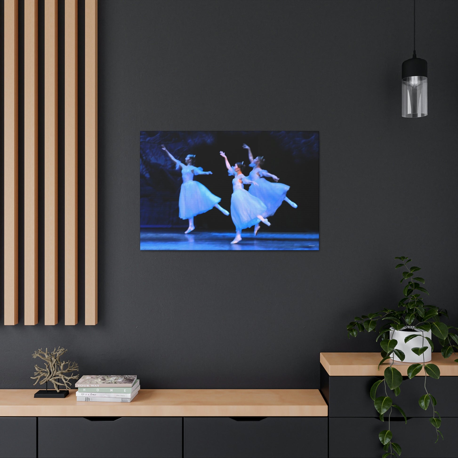 a photo of a painting in a home setting of three ballerinas performing on a stage dressed in white with light casting hues of blue