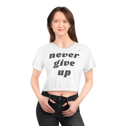girl shown wearing a crop tee shirt that says never give up. Charcoal gray lettering on white shirt.