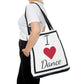 Dance tote bag with I heart dance written on opposite side of ballerina printed side, white background black trim, lettering and red heart. Handles are black.