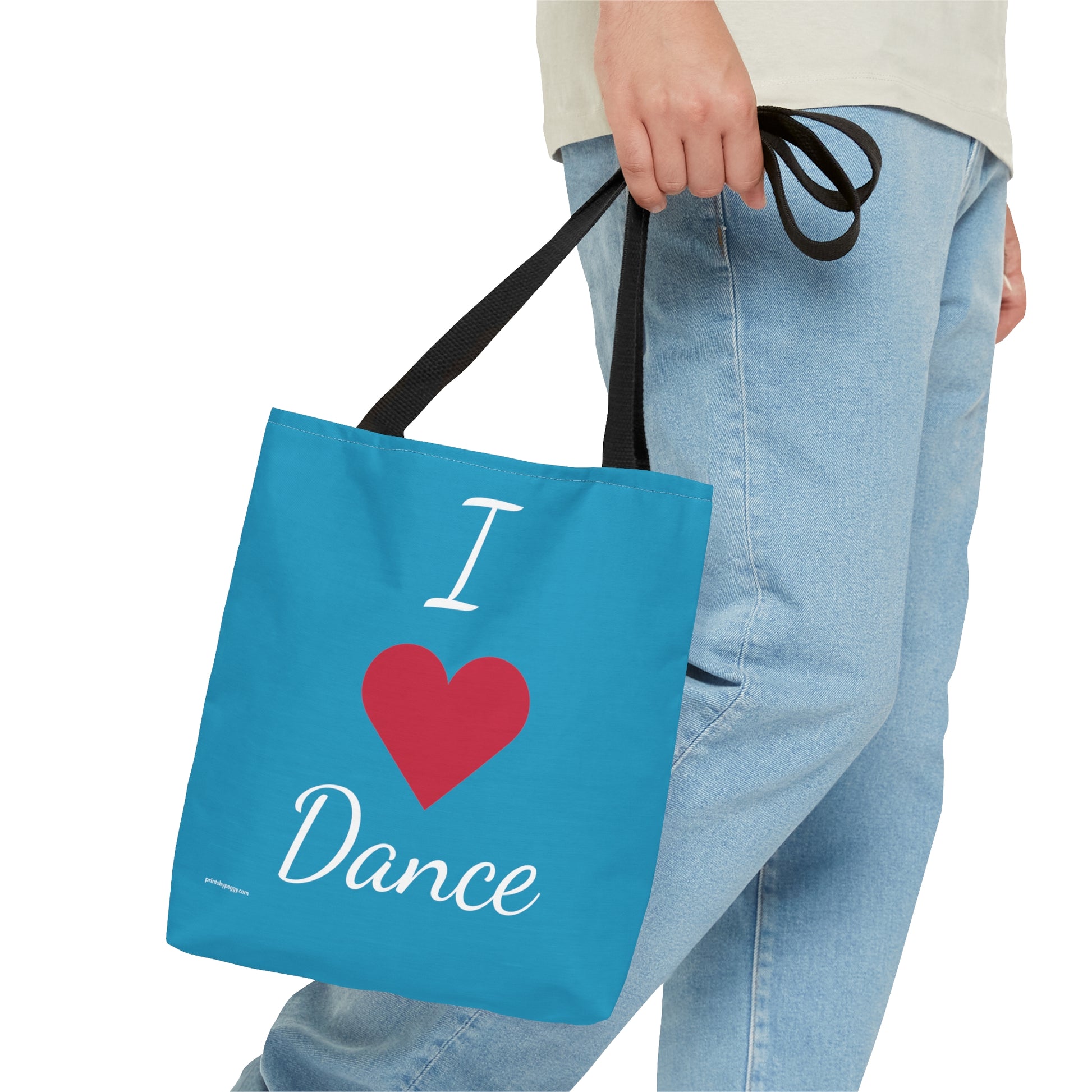 Aqua blue dance tote bag being carried in hand. Black strap. I heart dance with a red heart instead of the word.