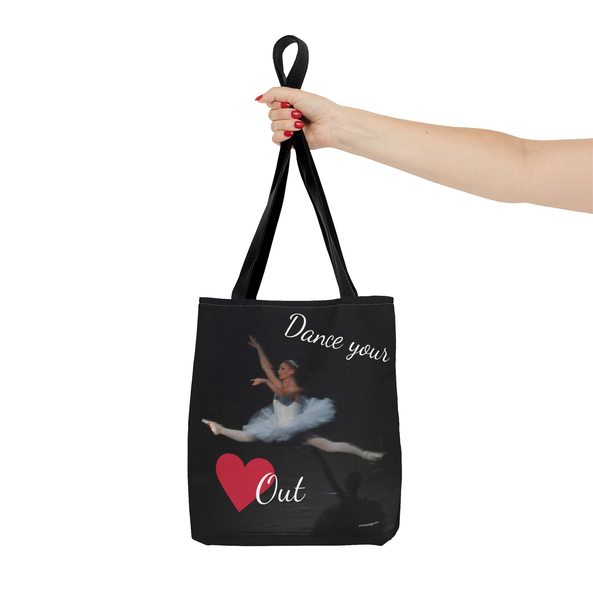 Black dance tote bag being carried in hand. Image is on both sides, ballerina jumping in mid air wearing a white tutu. Dance your heart out. Bag is black, white and red.