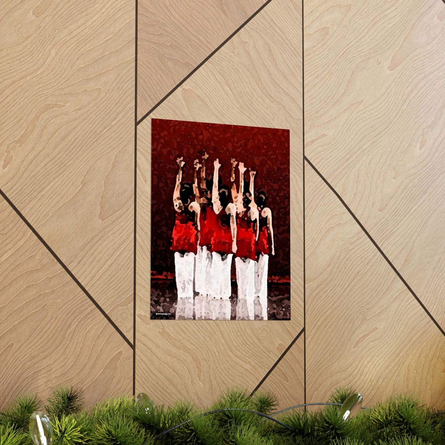 Poster hanging on a brown wall of seven modern dancers pictured from the rear with one hand outstretched wearing red and white costumes on stage with a red back drop