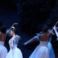 detail section of ballerinas dressed in white performing on stage