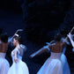 detail section of ballerinas dressed in white performing on stage