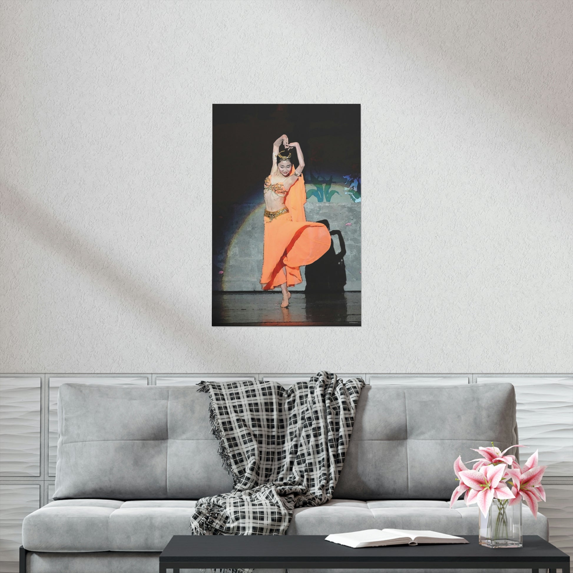 Poster hanging on a white wall of a dancer in orange belly dancer costume performing on stage