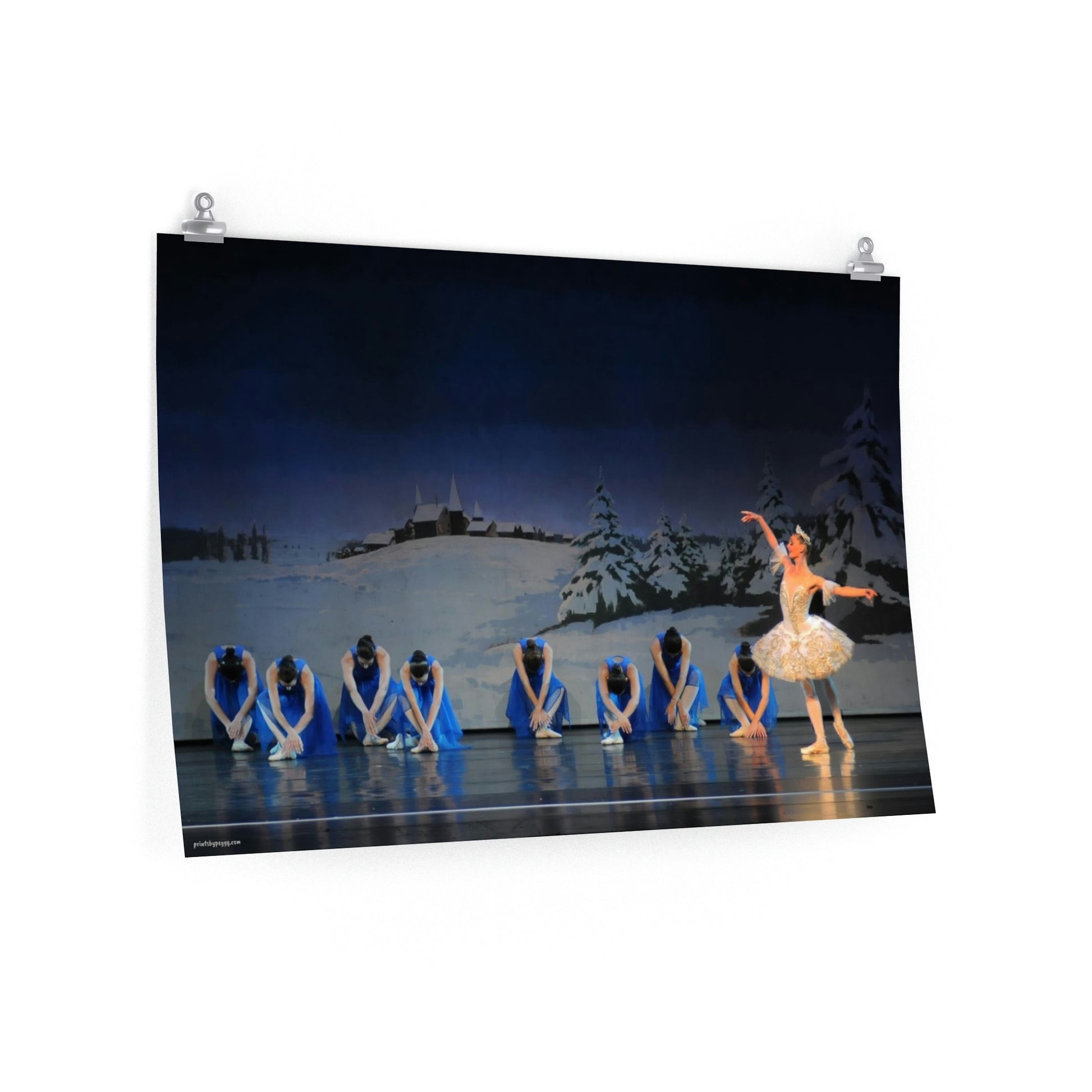 poster of artwork of prima ballerina  performing on stage with a winter scene backdrop and 8 girls bowing dressed in bright blue