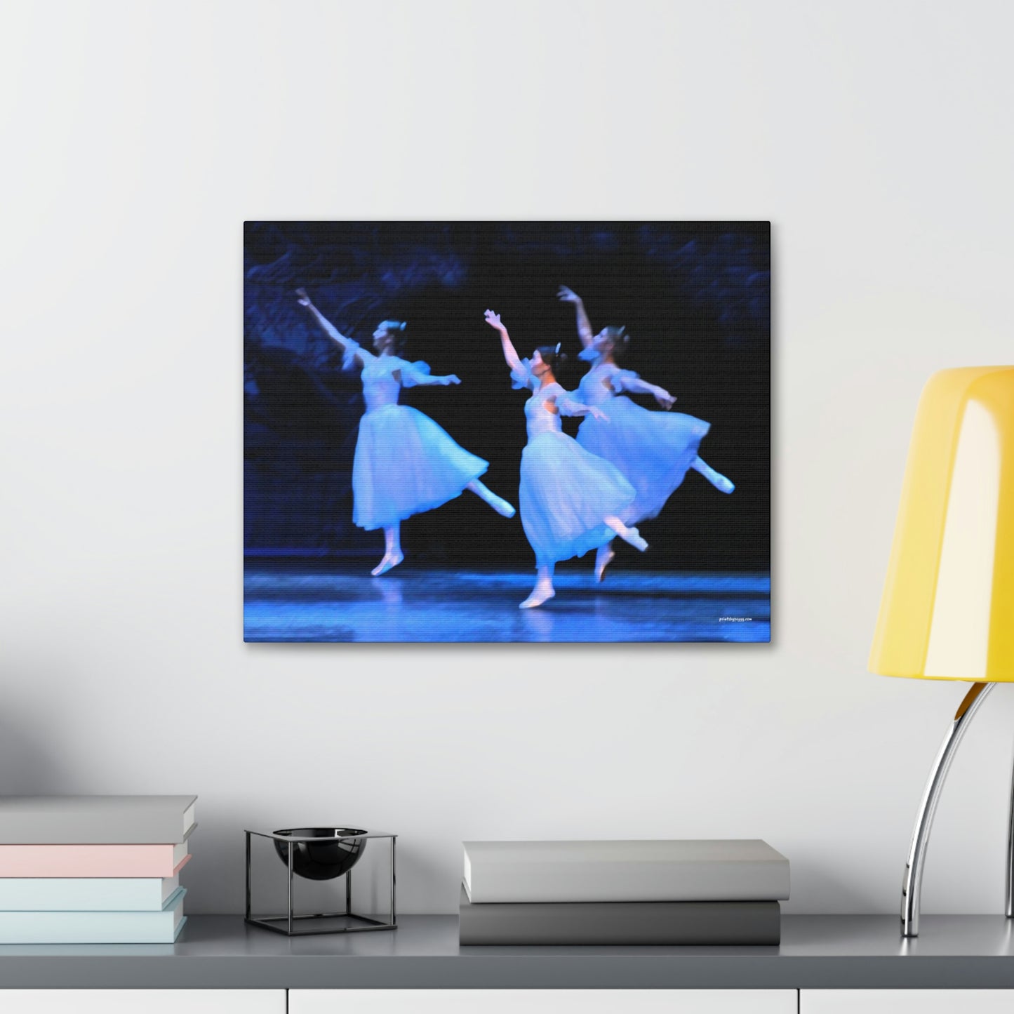 three ballerinas performing on stage with light casting blue hues on white dresses