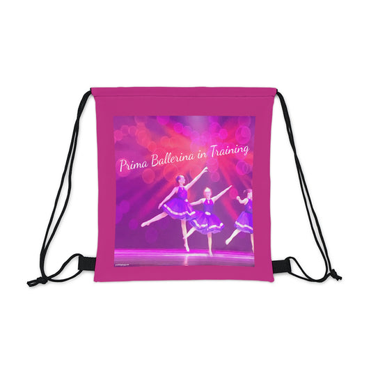 Hot pink drawstring bag text saying Prima Ballerina in Training with youth dancers in purple ballet costumes