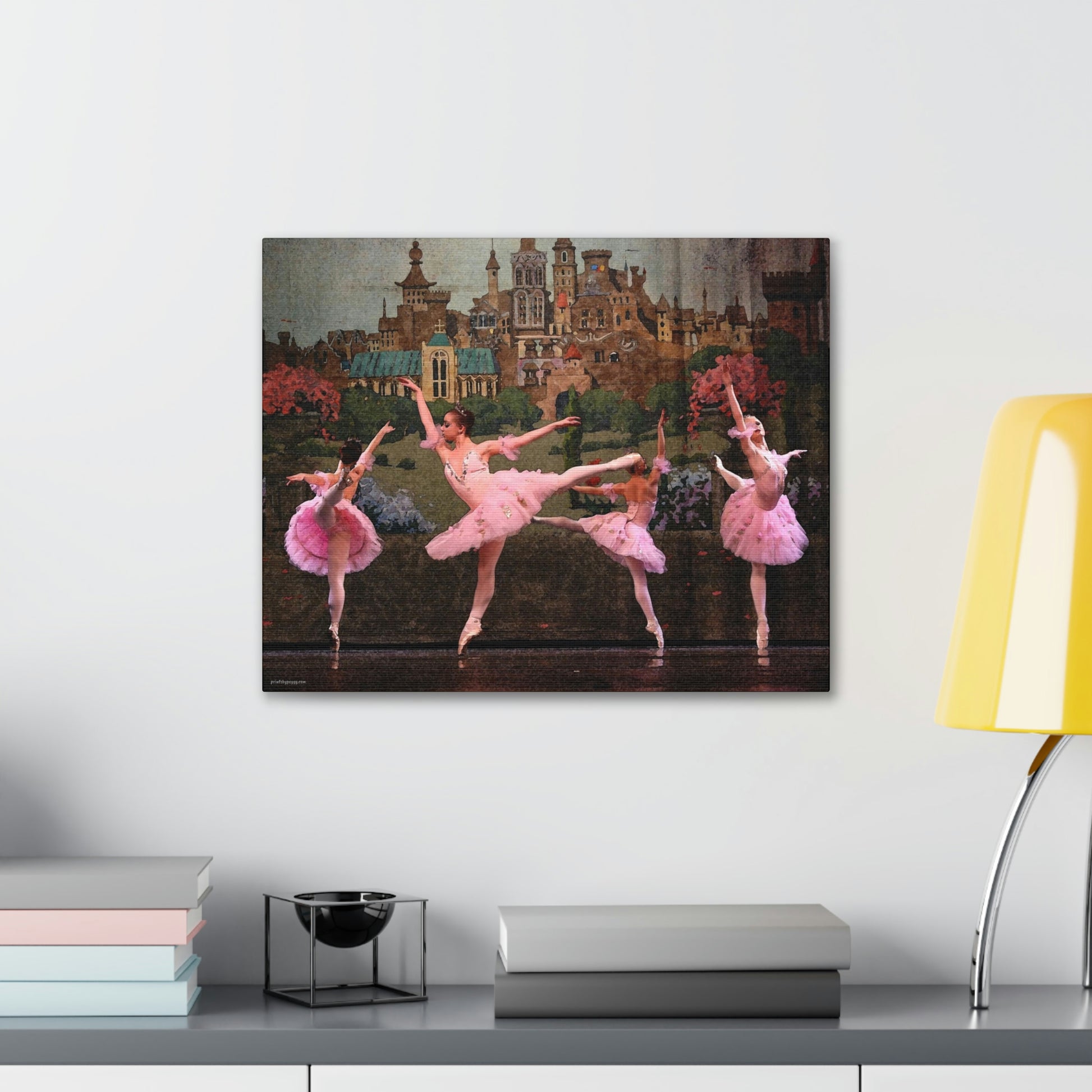 painting hanging over a desk of Four ballerinas dancing in a circle on stage with a castle backdrop dressed in pink