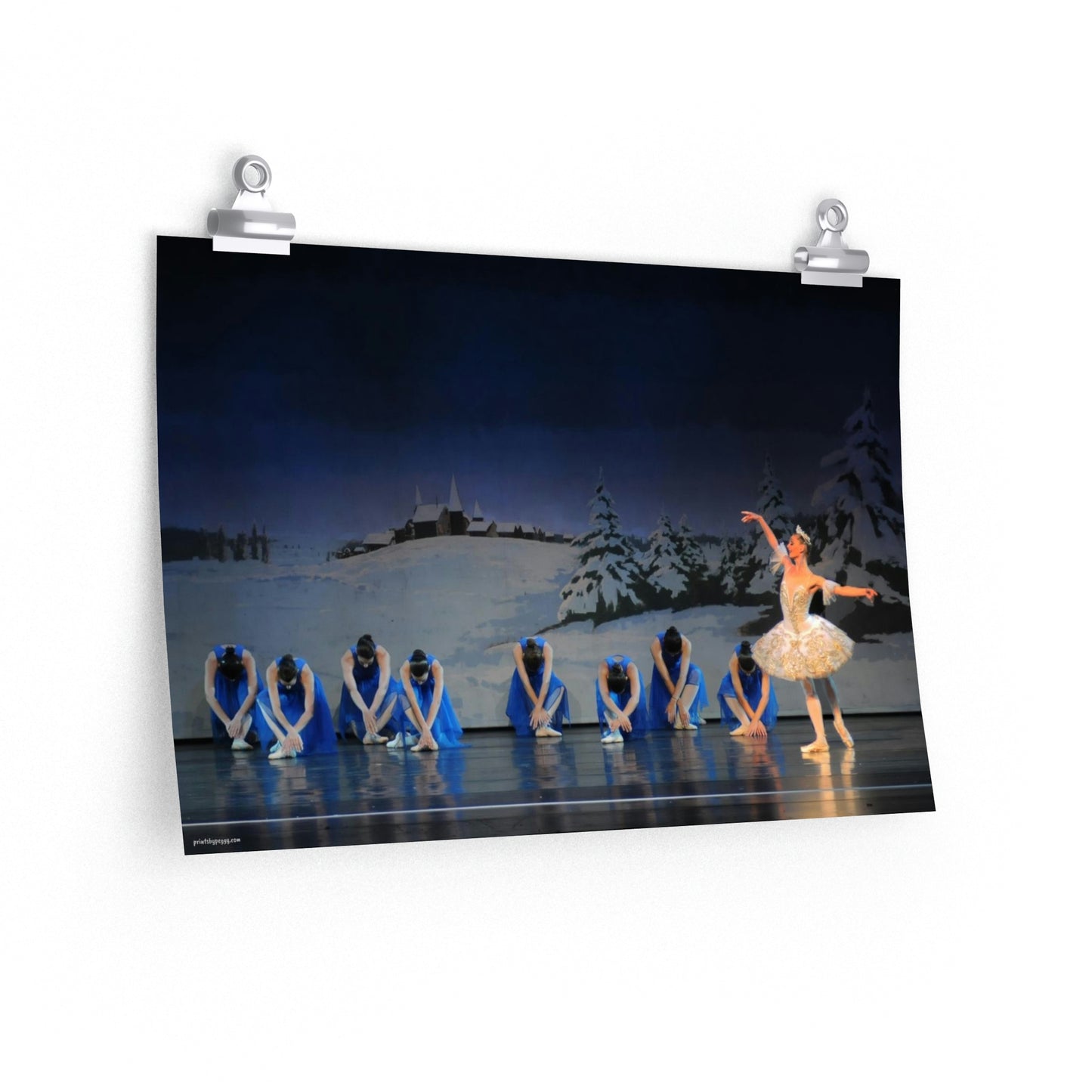 poster of artwork hanging on a wall of prima ballerina with 8 girls bowing dressed in blue performing on stage with a winter scene backdrop