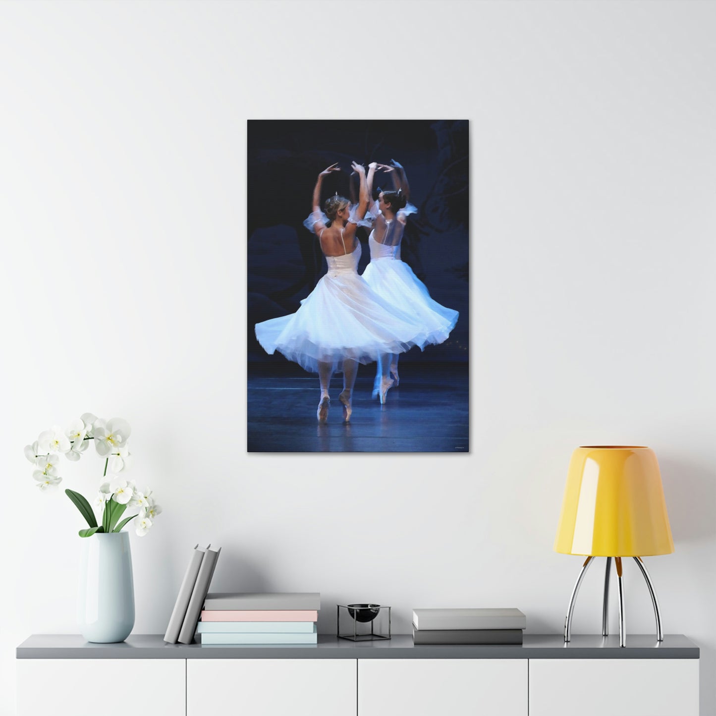 painting of two ballerinas wearing tiaras and white dresses on point hanging on a white wall over a desk