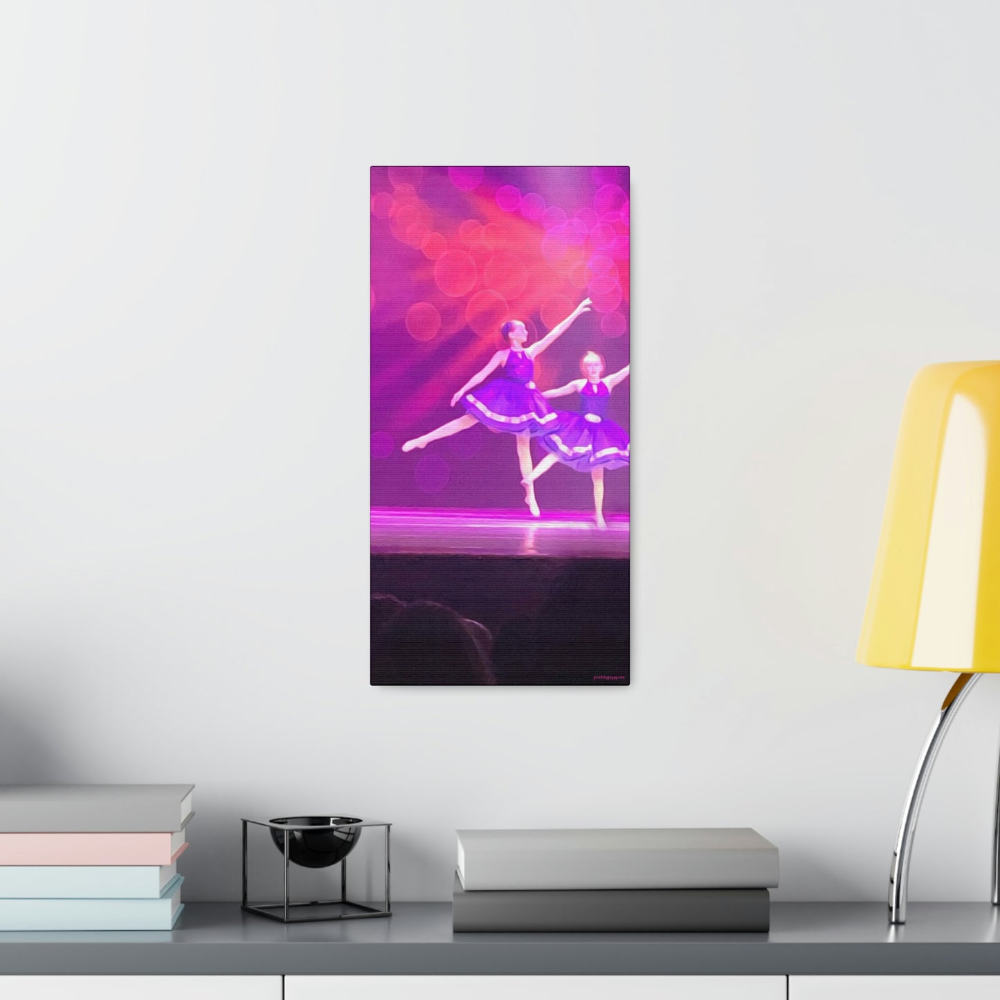 An oil canvas print hanging on a wall over a desk showing Young female ballet dancers in purple with a hot pink and purple backdrop 