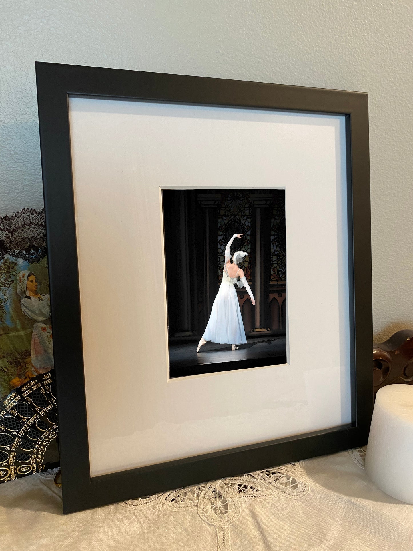 photo of a framed print of graceful ballet dancer from the back dressed in white performing on stage