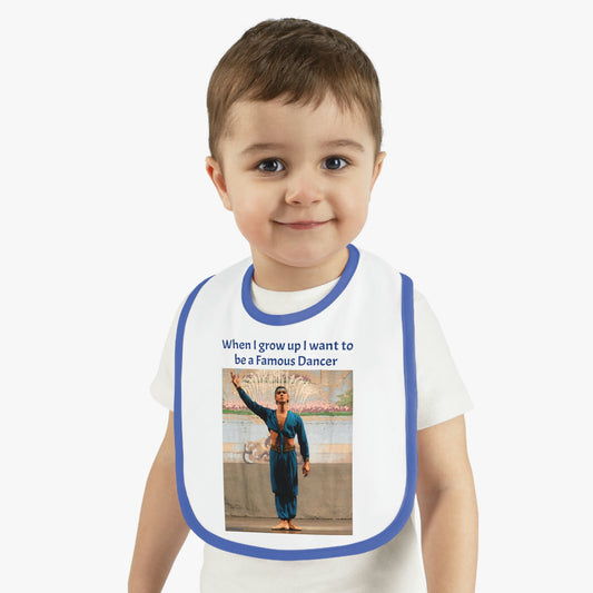 Baby bib with a picture of a male dancer dressed in blue with the phrase, when I grow up I want to be a famous dancer written on the front. bib is white with dark blue trim being worn by a little boy.