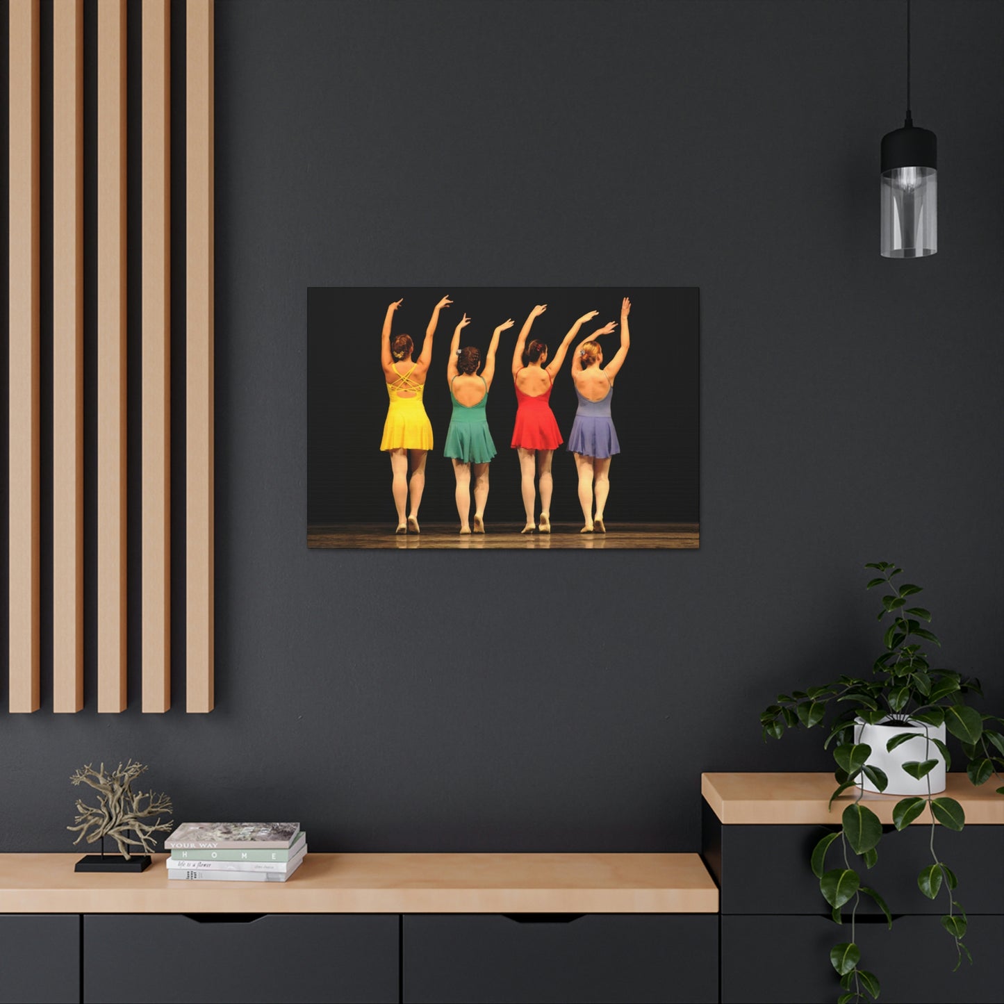 Art image hanging on the wall in a home setting of a painting of four modern dancers from the rear on stage in bright costumes