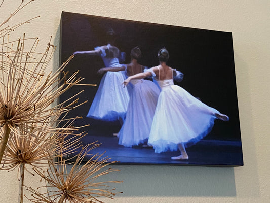 a photograph of a painting hanging on a wall in a home setting of three Graceful ballet dancers performing on stage shown from the rear dressed in white