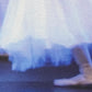 a detail section showing a skirt and ballet shoe