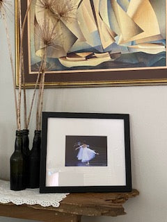 A photo of artwork of three ballet dancers in white dresses printed, matted and framed in a livingroom setting