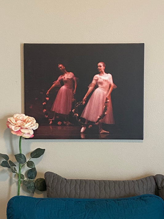 Artwork hanging on the wall of a home of two ballerinas in pink posing with wreathes of pink flowers on a dark background