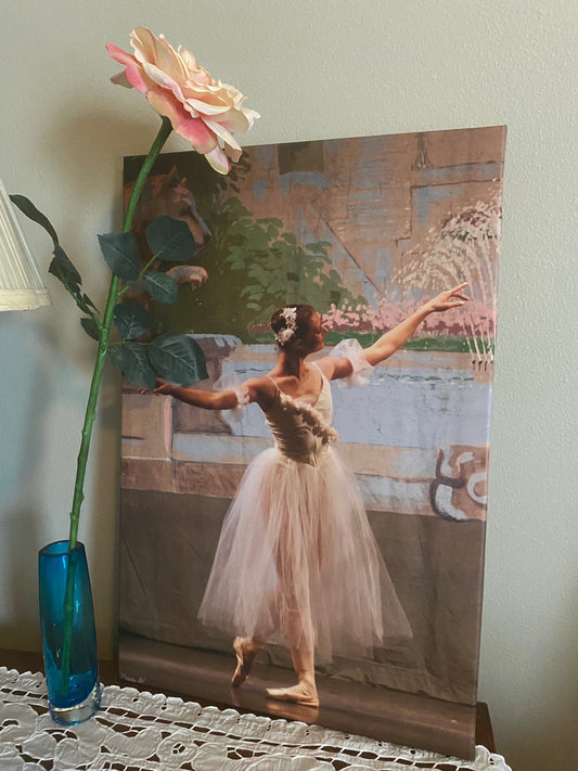 A photo of a painting of a ballerina in white gracefully posed on stage with a colorful backdrop or background