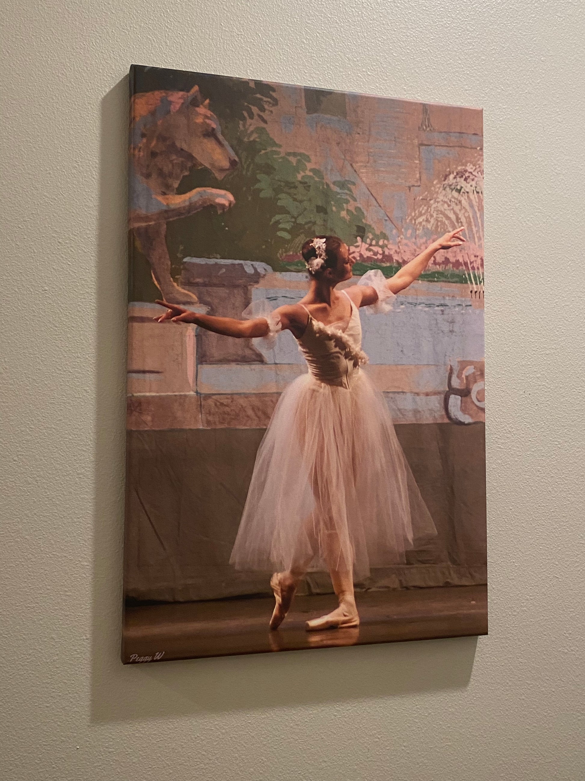 A photo of an oil painting hanging on a wall of a graceful ballerina performing on stage in a white dress with a colorful background