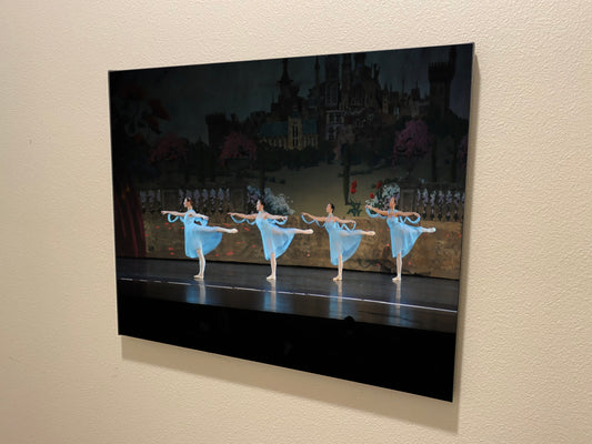 painting hanging on a wall of four ballerinas on stage in blue costumes