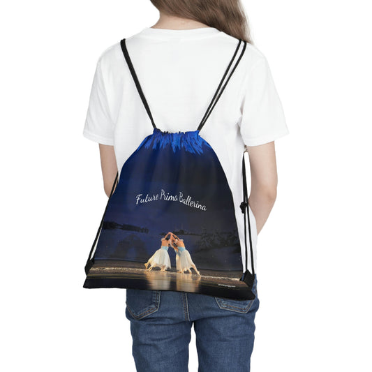 Drawstring bag being worn as a backpack on a model. Bag says Future Prima Ballerina with ballerinas performing on stage in blue and white costumes. Bag color is basically blue, white and black.