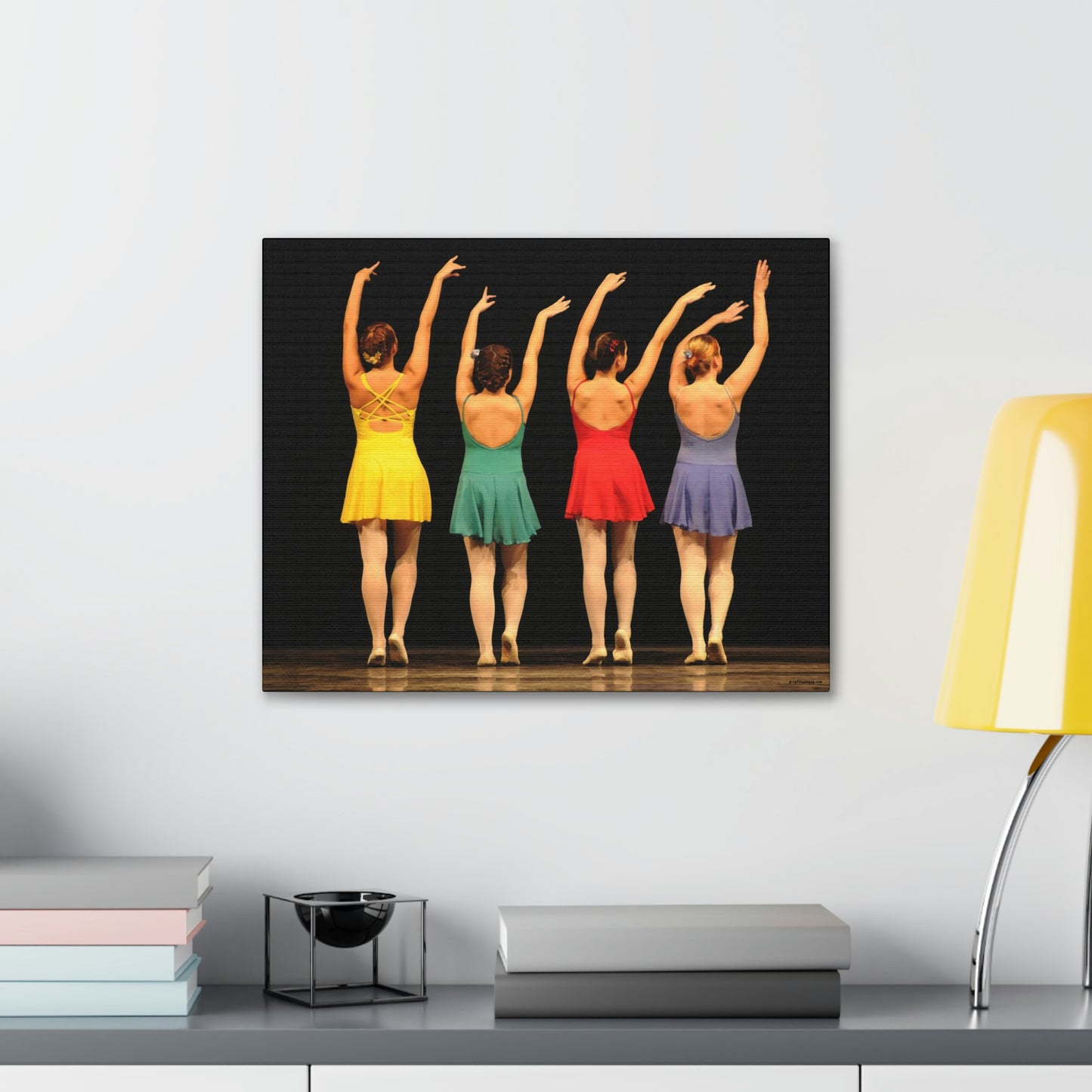 Art image hanging on the wall in a home setting of a painting of four modern dancers from the rear on stage in bright costumes