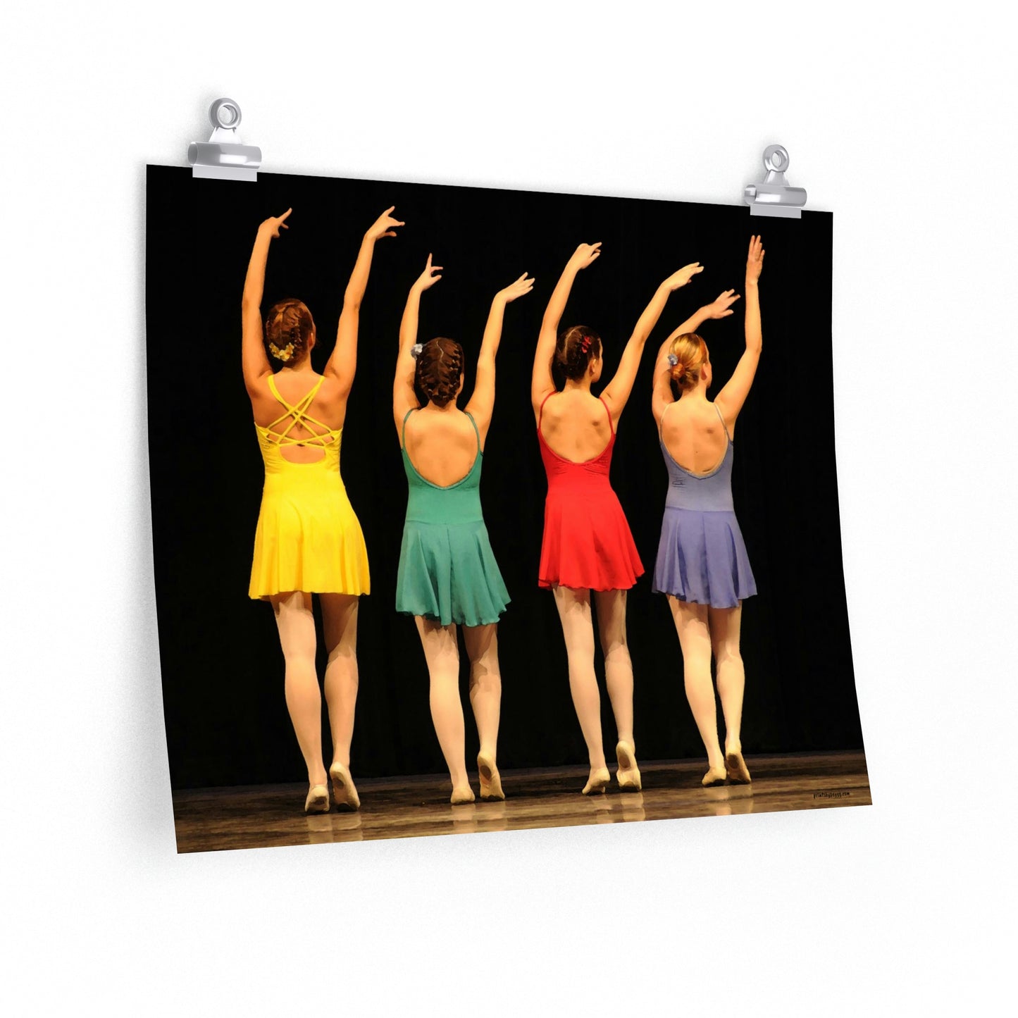 a poster of four dancers in a line on stage dressed in bright colored costumes of yellow, green, red and purple shown from the rear with their arms in the air