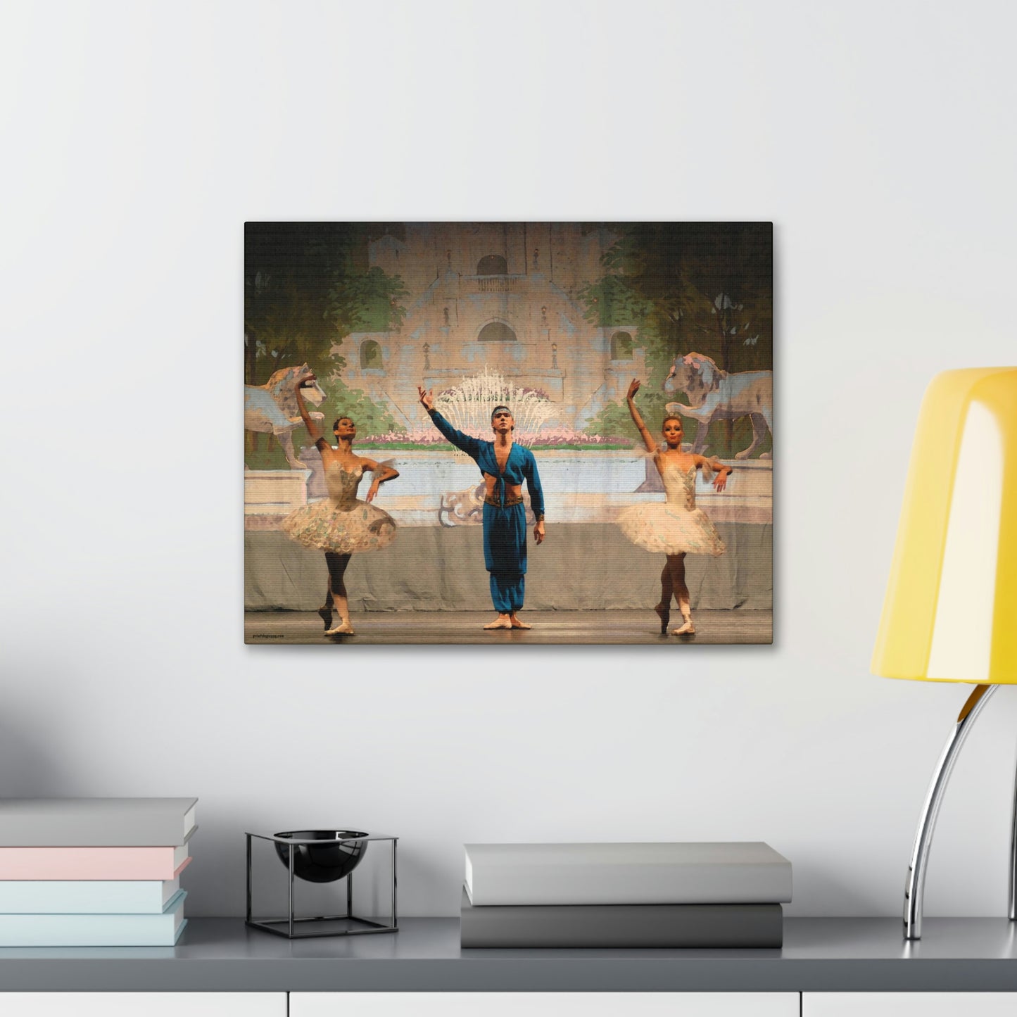 painting hanging on the wall over a desk of 3 dancers from a Nutcracker performance. Two female dancers with a male dancer in the center. Arabian scene.