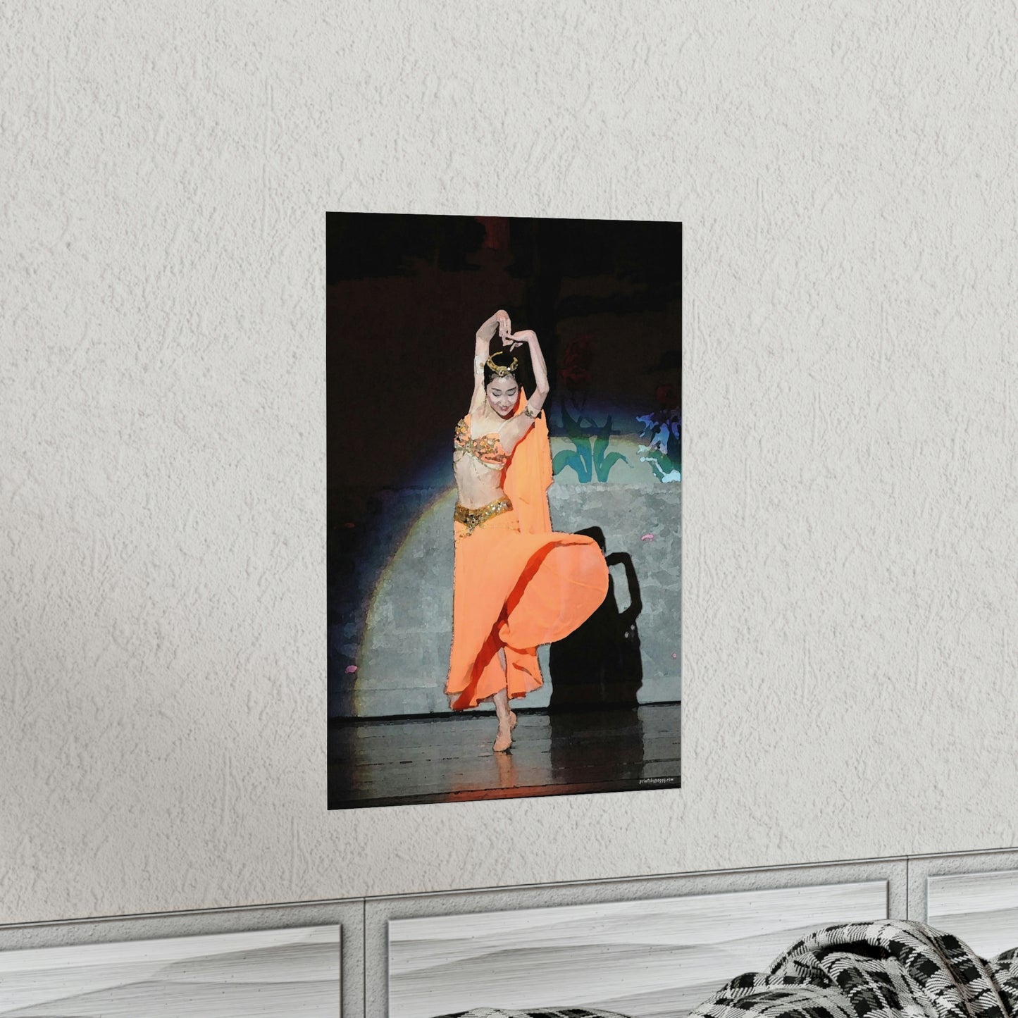 Poster hanging on a white wall of a dancer in orange belly dancer costume performing on stage