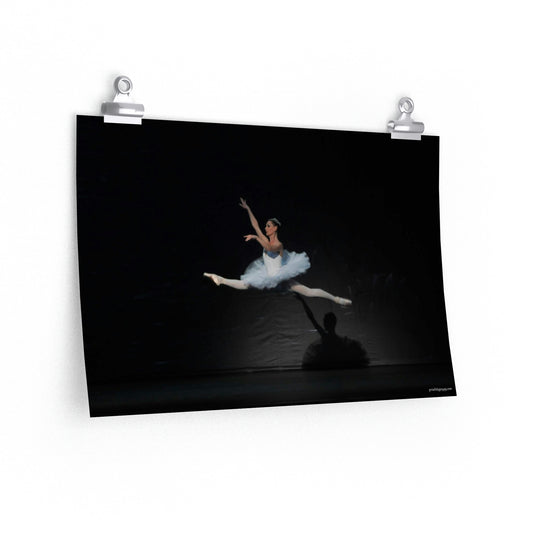 Prima Ballerina is in a full leap in a white tutu with a black background