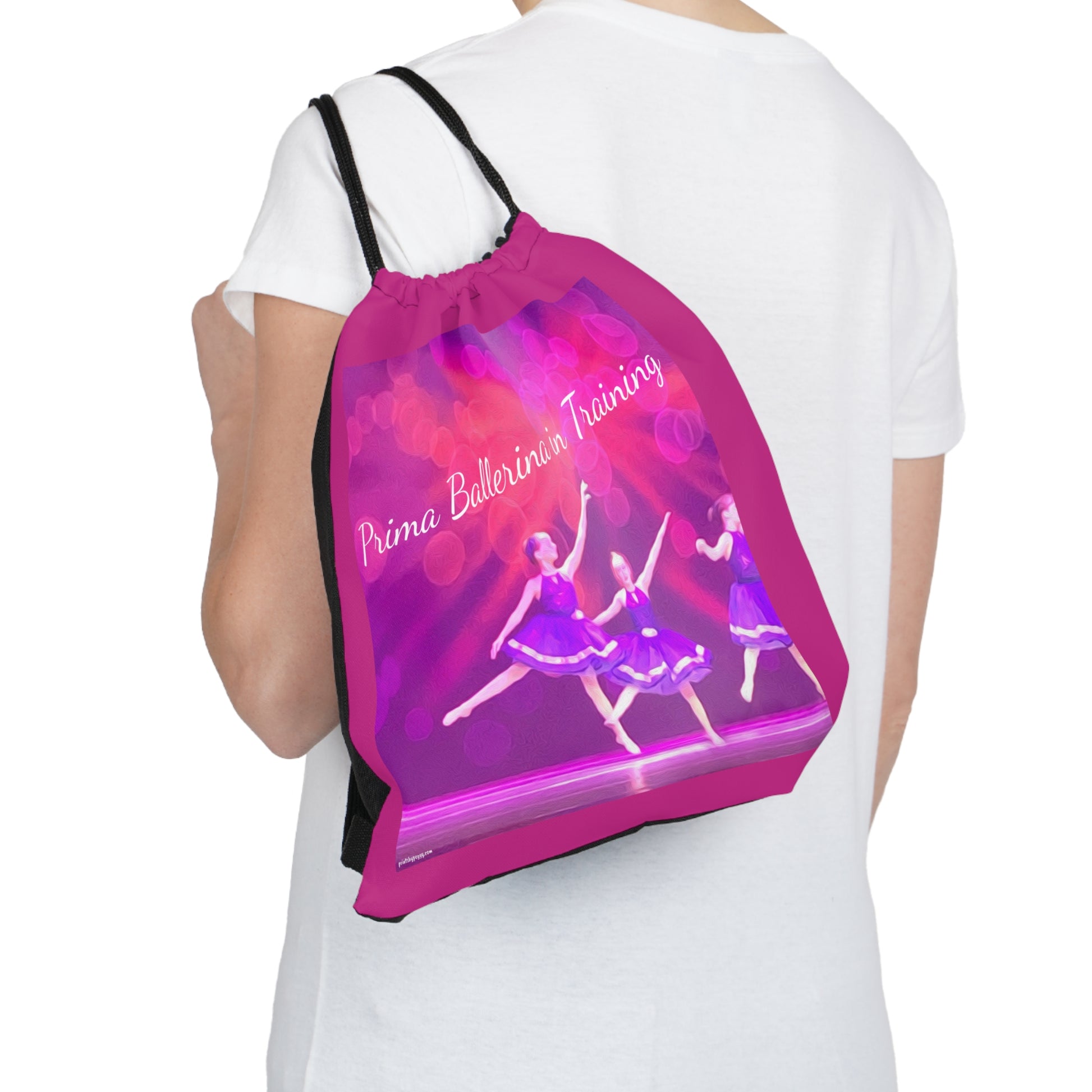 Hot pink drawstring bag text saying Prima Ballerina in Training with youth dancers in purple ballet costumes